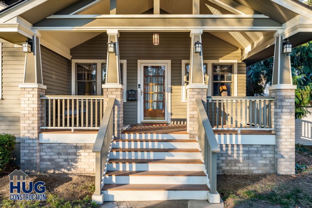 Front porch of a suburban house featuring remodels and additions at sunset with the company logo "hug construction" overlaying the image.