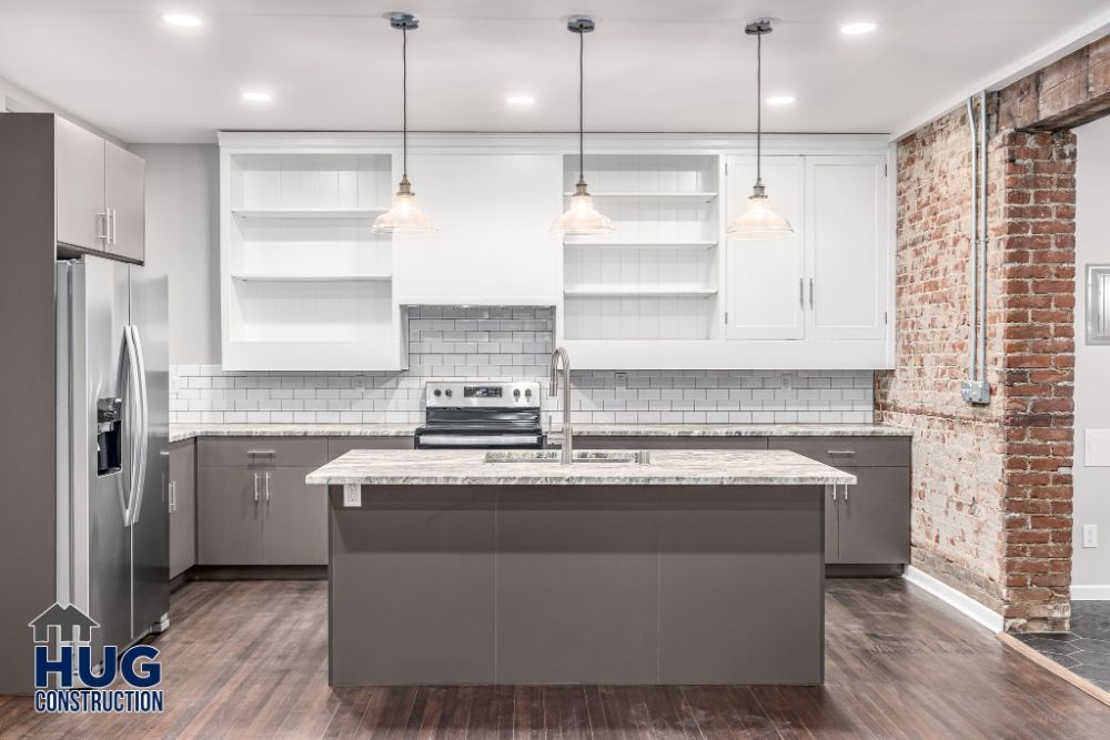 Modern kitchen interior with stainless steel appliances, white cabinetry, subway tile backsplash, exposed brick wall, and sleek additions.