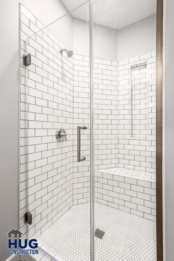 Modern corner shower stall remodels with white subway tiles and glass door.