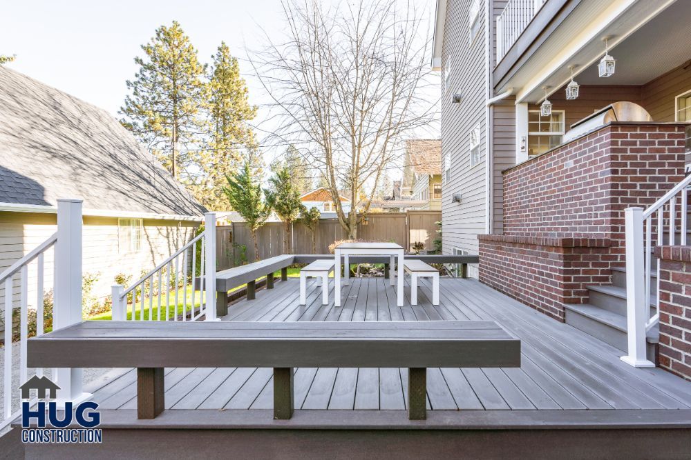 A spacious backyard with new remodels, including a wooden deck and patio furniture, near a residential building.