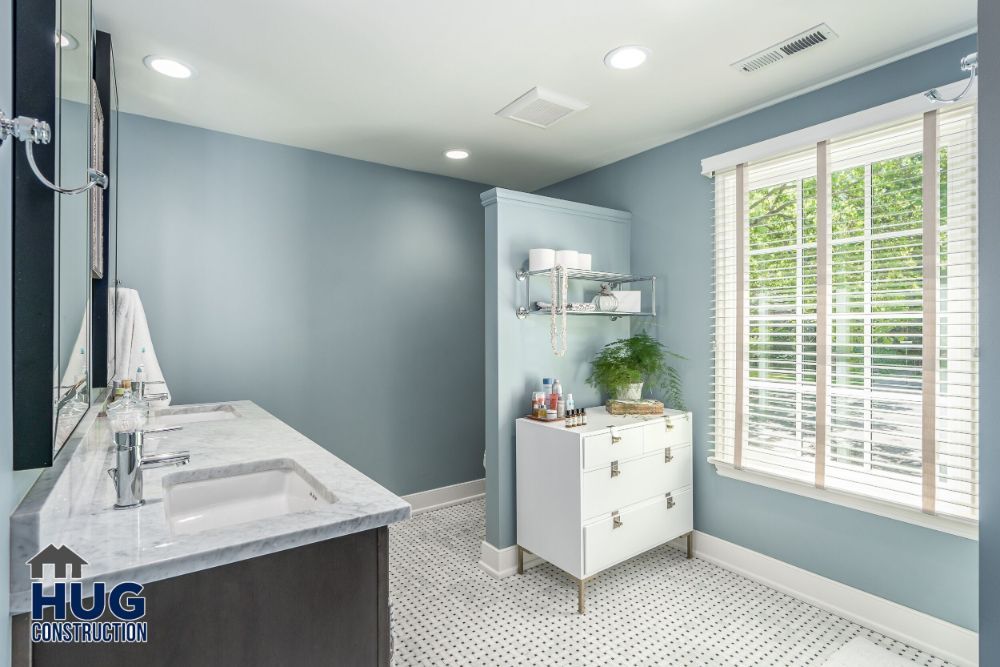 Modern bathroom interior with blue walls, white vanity, and tiled flooring features recent remodels and additions.