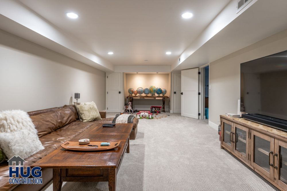 A well-lit basement living space featuring remodels such as a leather couch, a television, and a children's play area in the background.