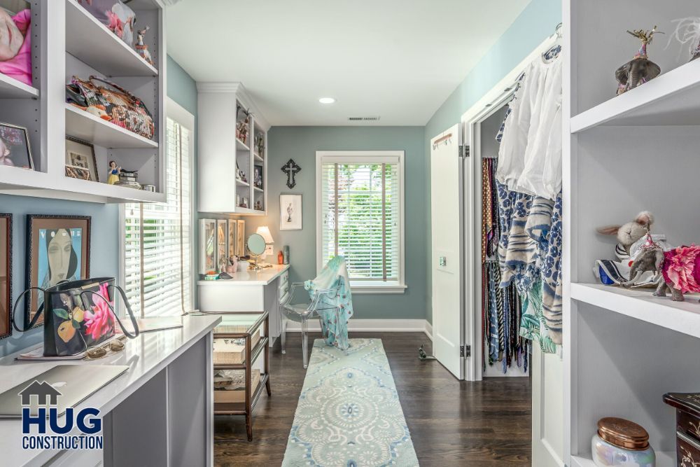 Spacious walk-in closet with remodels and additions, featuring built-in shelving, a centered dressing table, and a soft blue color scheme.