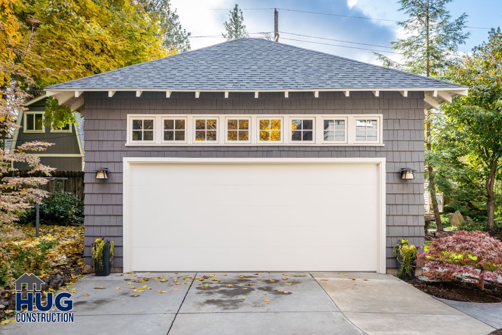 Detached two-car garage with grey siding on a residential property, featuring recent remodels and additions.