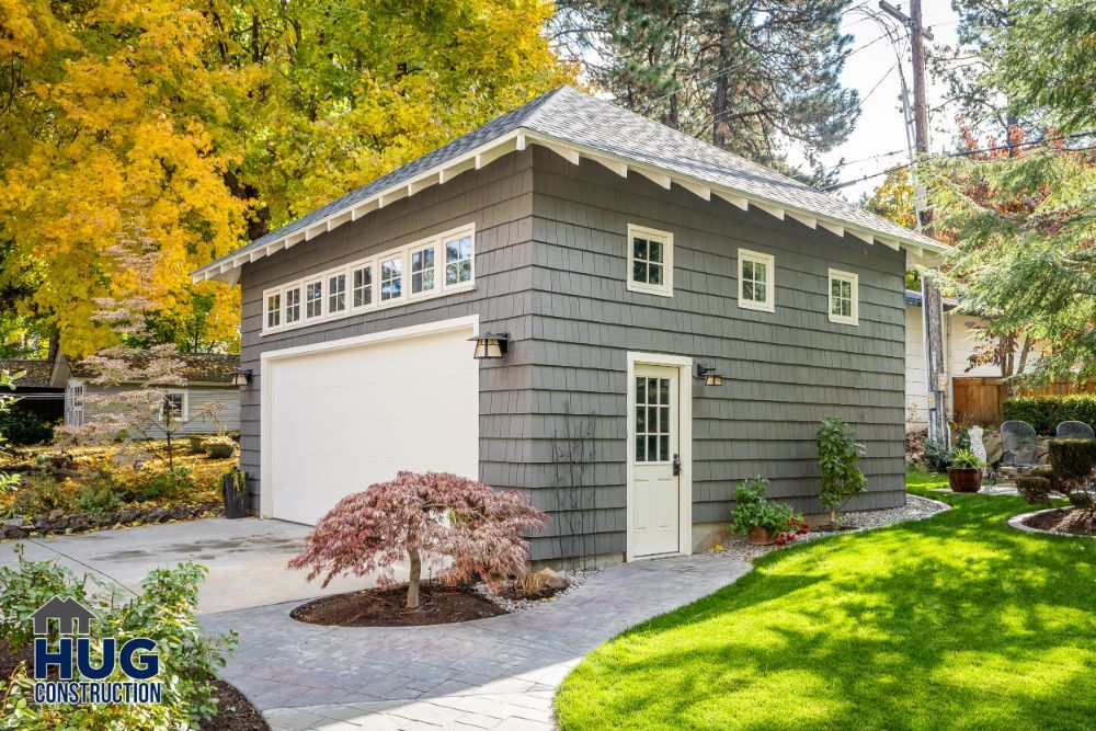 Detached garage with living space above in a landscaped backyard, featuring remodels and additions.