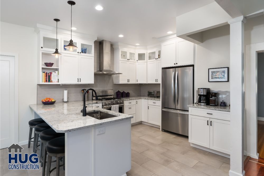 Modern kitchen interior remodels with stainless steel appliances, white cabinetry, and a central island with bar stools.