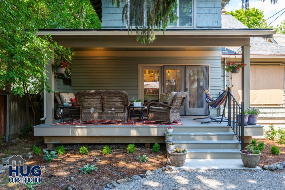 A cozy, well-maintained porch with comfortable seating and decorative plants in front of a residential home, enhanced by recent remodels and additions.