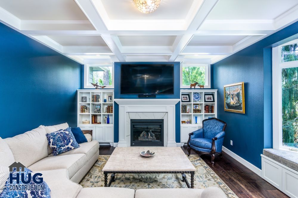 Elegant living room remodels with blue walls, white built-in shelves, and a central fireplace under a mounted television.