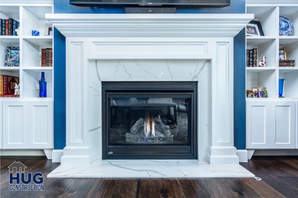 A modern fireplace with a white mantel, flanked by built-in bookshelves and additions, set against a blue wall.