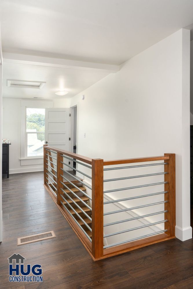 Modern hallway with wooden floor, cable railing system, and additions by Hug Construction.