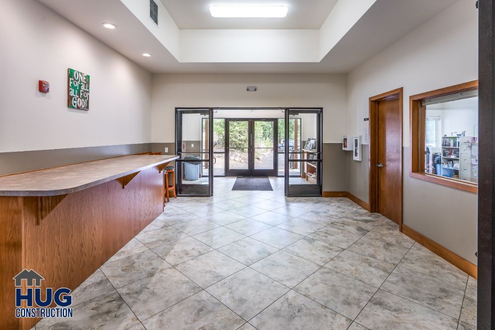 Spacious lobby area with a reception desk and tile flooring, leading to double entrance doors, crafted by a Commercial Contractor Spokane.