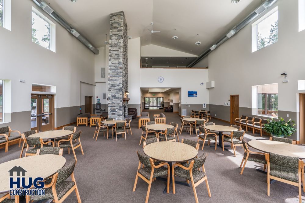 Spacious lobby area with seating and a central stone fireplace in a modern building designed by a leading Commercial Contractor in Spokane.