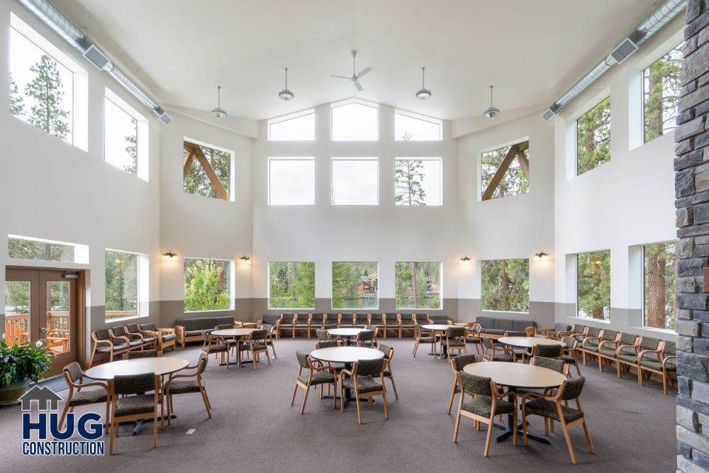 Spacious and well-lit conference room, designed by a leading Commercial Contractor in Spokane, with multiple tables and chairs, surrounded by large windows and stone accents.