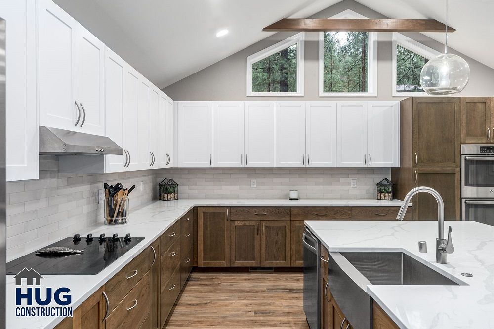 Modern kitchen interior remodels with white and wood cabinetry, stainless steel appliances, and a skylight.
