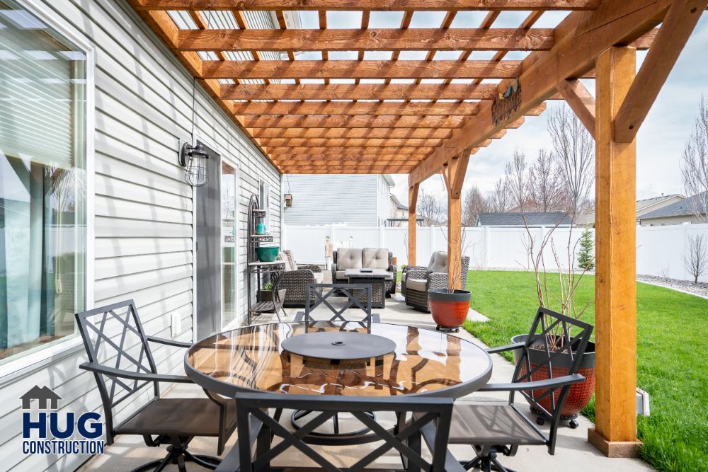 Residential patio with remodels and additions, including a wooden pergola, furniture set, and a manicured lawn.