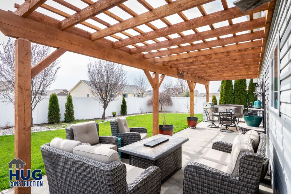 A residential backyard patio, enhanced with remodels and additions, furnished with a woven outdoor seating set under a wooden pergola.