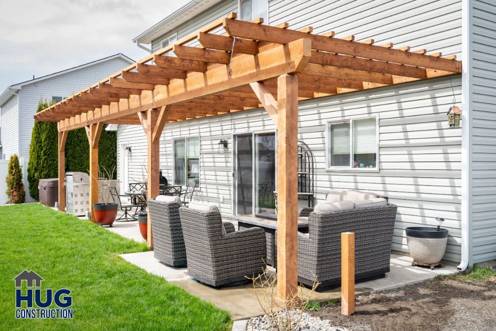 Wooden pergola remodels adjacent to a house, with outdoor seating area underneath.