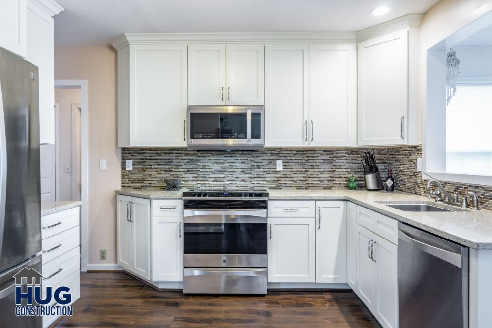 Modern kitchen remodel with white cabinetry, stainless steel appliances, and mosaic backsplash.