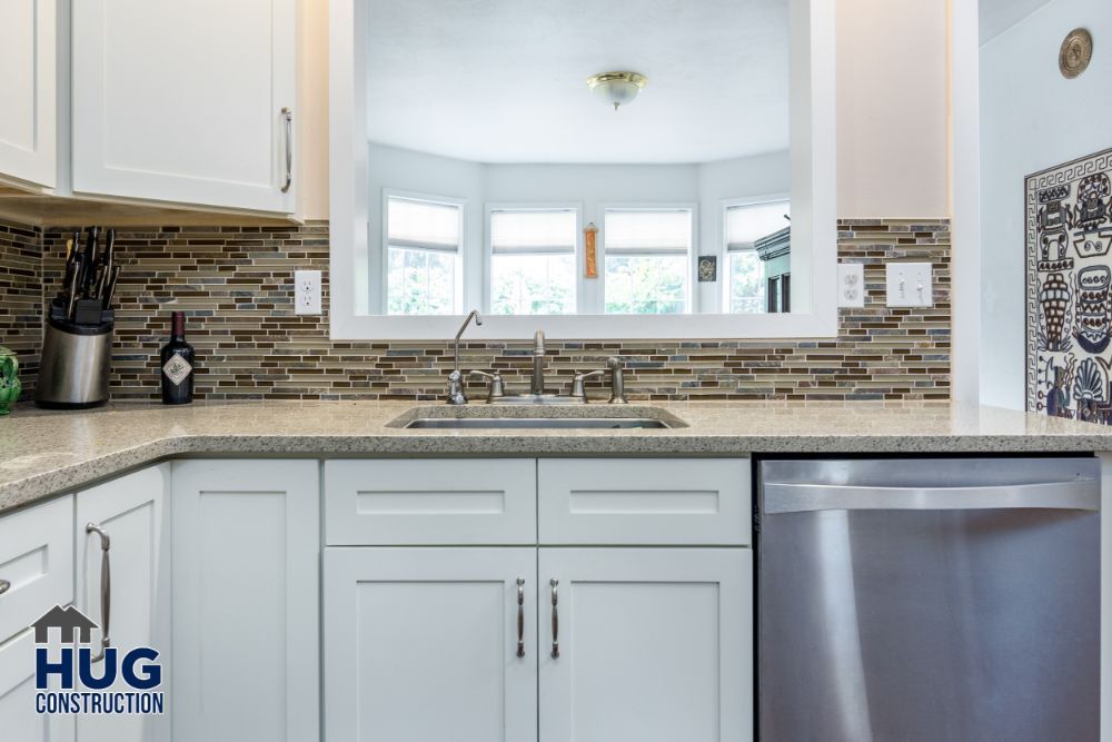 Modern kitchen interior remodels featuring white cabinets, stainless steel appliances, and a mosaic tile backsplash.