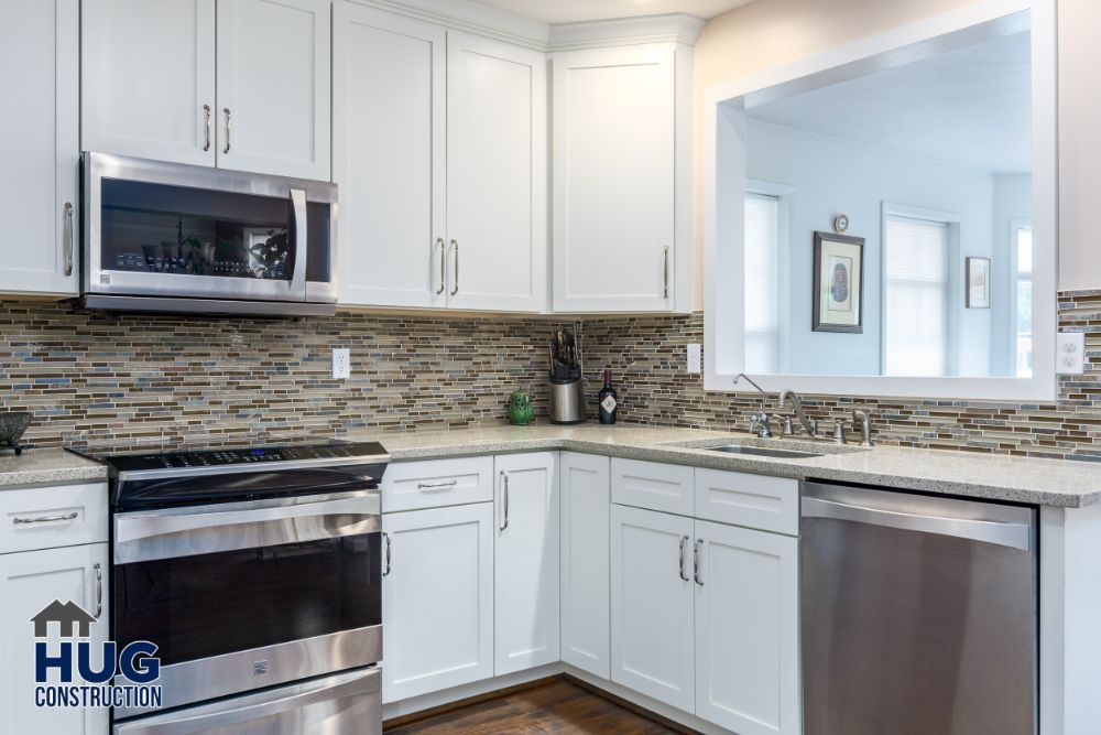 Modern kitchen remodel with white cabinetry and stainless steel appliances.