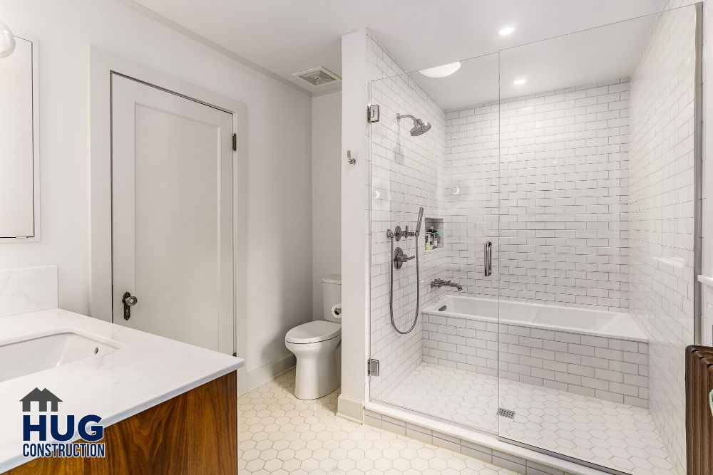 Modern bathroom remodels with a glass shower enclosure, white subway tiles, and hexagonal floor tiles.