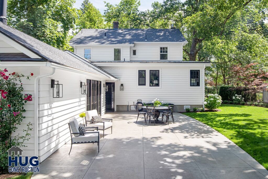 A well-maintained backyard of a suburban house with outdoor seating, remodels, and additions in the lush garden.