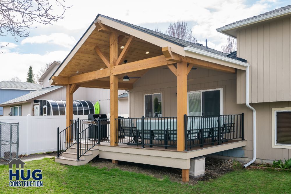 Newly constructed wooden porch extension and remodels with a black railing on a residential home.