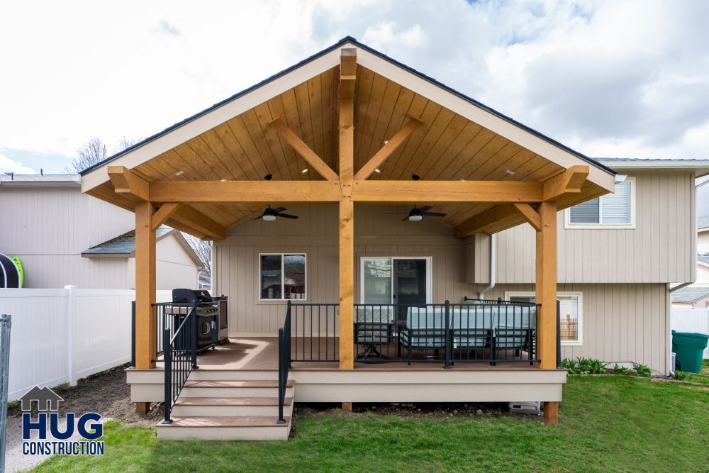 A wooden backyard patio cover with outdoor furniture, remodels and additions, and stairs leading to the lawn.