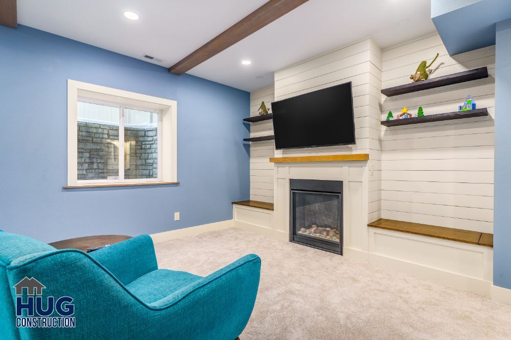 A modern living room featuring remodels and additions, including a wall-mounted television above a fireplace, blue furnishings, and built-in shelving with decorative items.