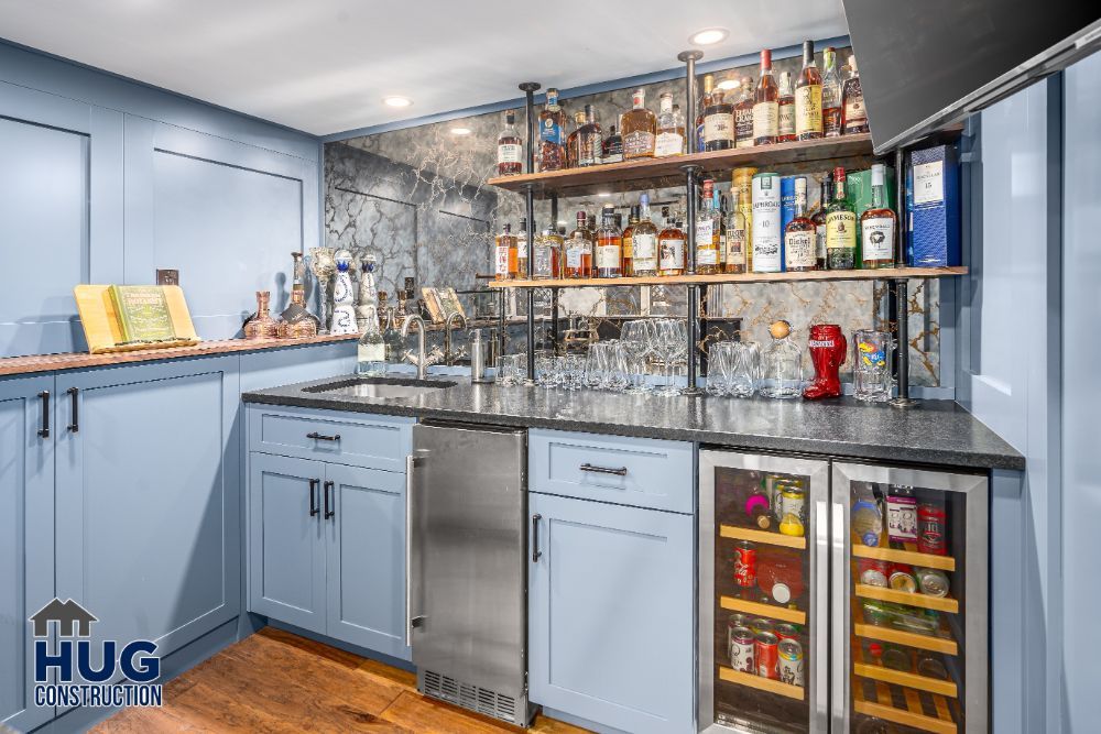 A modern home bar, with a variety of spirits, stemware, and a refrigerator, set against a marble backsplash incorporates recent remodels.
