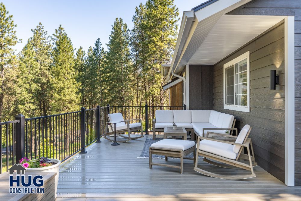 Spacious wooden deck remodels with modern outdoor furniture overlooking a forested area.