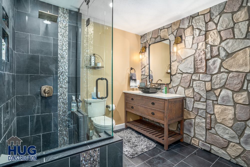 Modern bathroom with stone accent wall, glass shower, wooden vanity, and recent remodels.