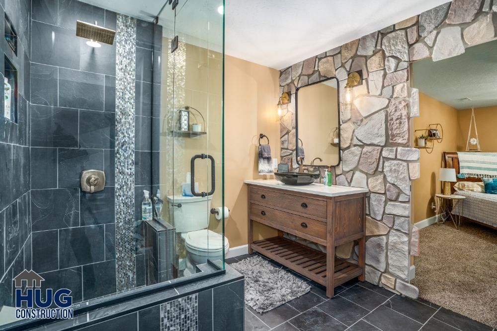 Modern bathroom remodels with stone accent wall, glass shower enclosure, and wooden vanity.