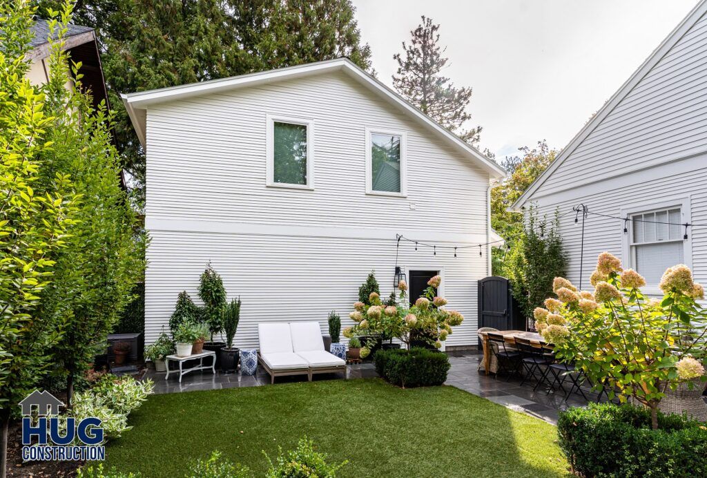 A well-kept backyard with manicured lawn, featuring a patio area with outdoor furniture for all projects and white siding on the house.