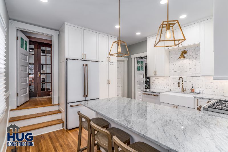Modern kitchen interior remodels with white cabinetry, marble countertops, and geometric pendant lighting.