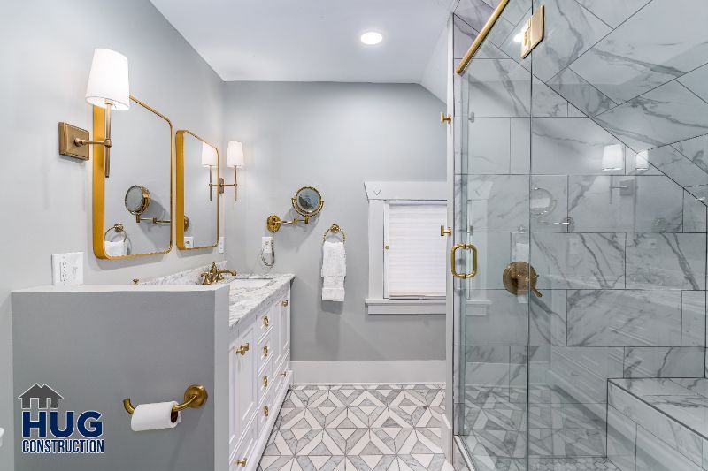 Modern bathroom remodels with marble tiles, glass shower, and gold fixtures.