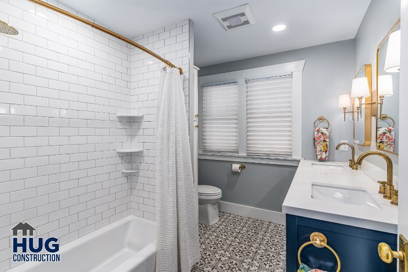 Modern bathroom remodels with white subway tiles, patterned floor, and navy blue vanity.