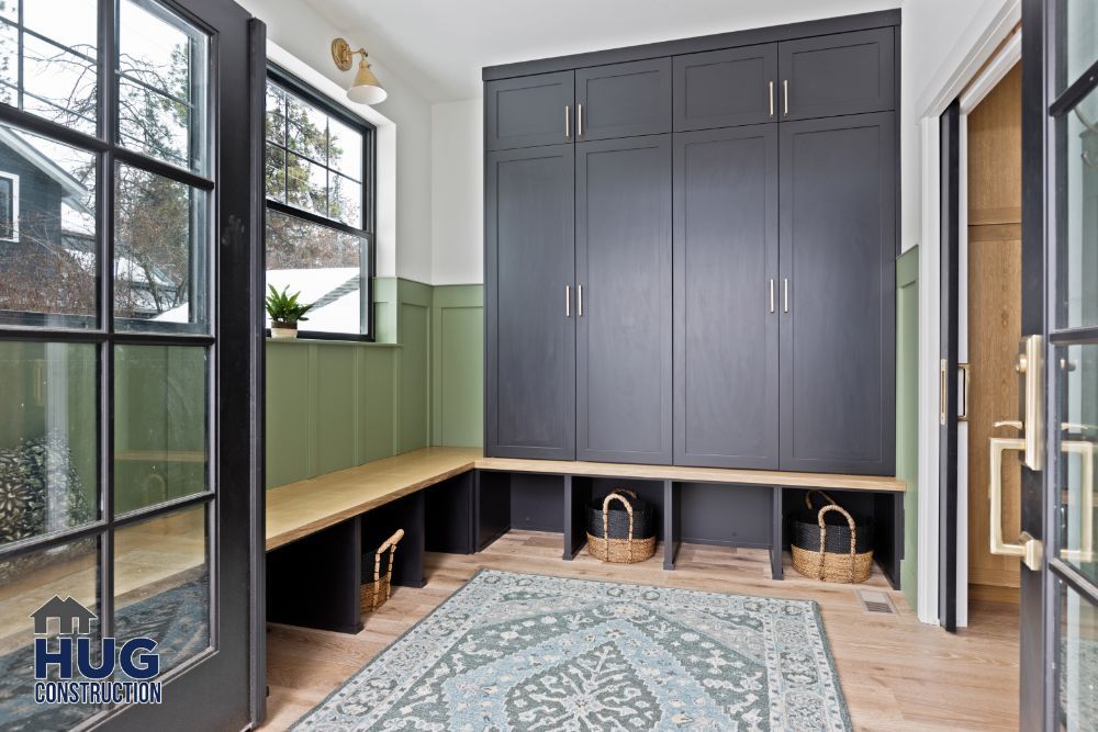 Modern mudroom remodels with built-in dark cabinetry, a bench with storage underneath, and a patterned area rug.
