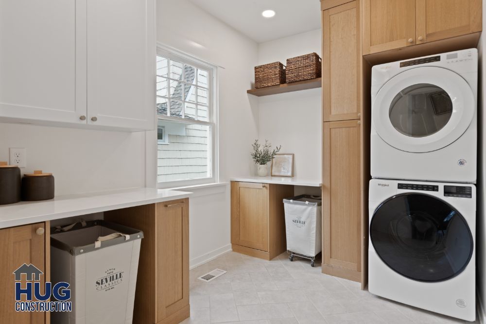 A modern laundry room remodel with white appliances and wooden cabinets.