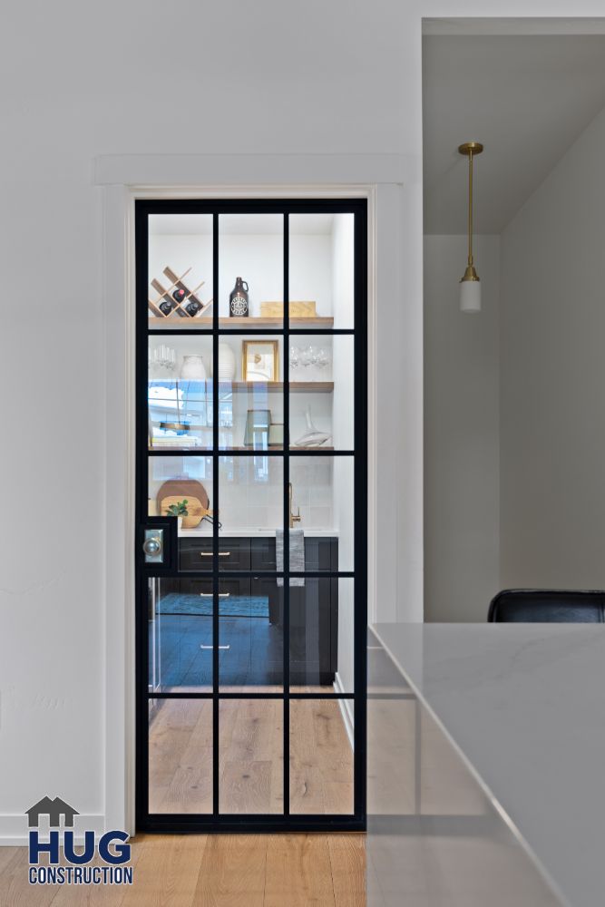 Elegant black-framed glass door leading to a modern kitchen with open shelving, perfect for remodels and additions.