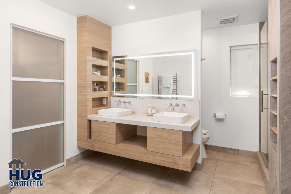 A modern bathroom featuring a double vanity with wooden cabinets, a large mirror, walk-in shower, and remodels.