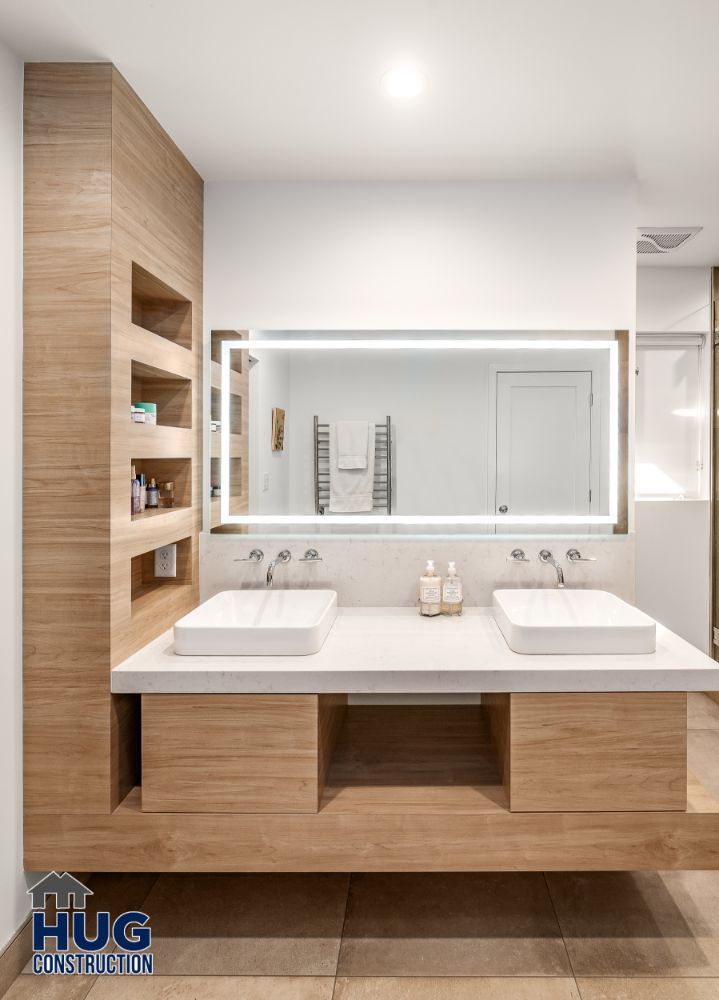 Modern bathroom remodels with double sinks, wooden vanity, and a large mirror.