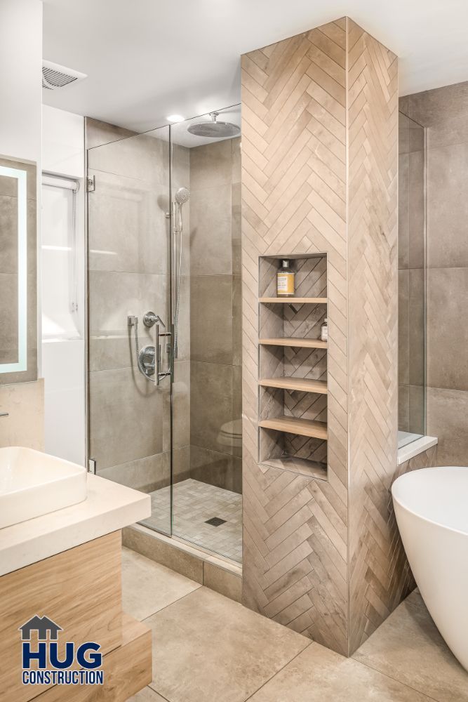 Modern bathroom remodels with glass shower enclosure, built-in shelving, and freestanding bathtub.