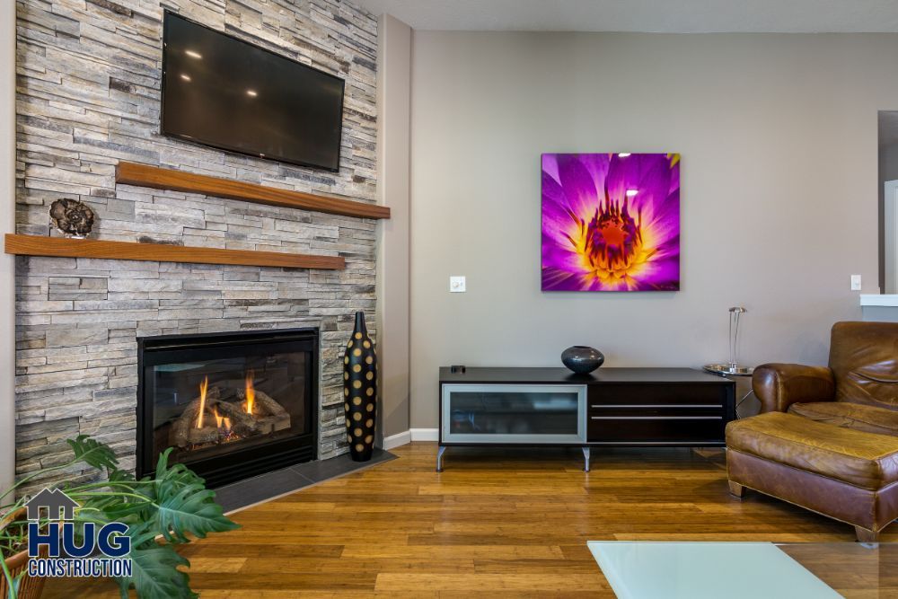 Modern living room interior with stone fireplace, wall-mounted tv, vibrant wall art, and stylish additions.