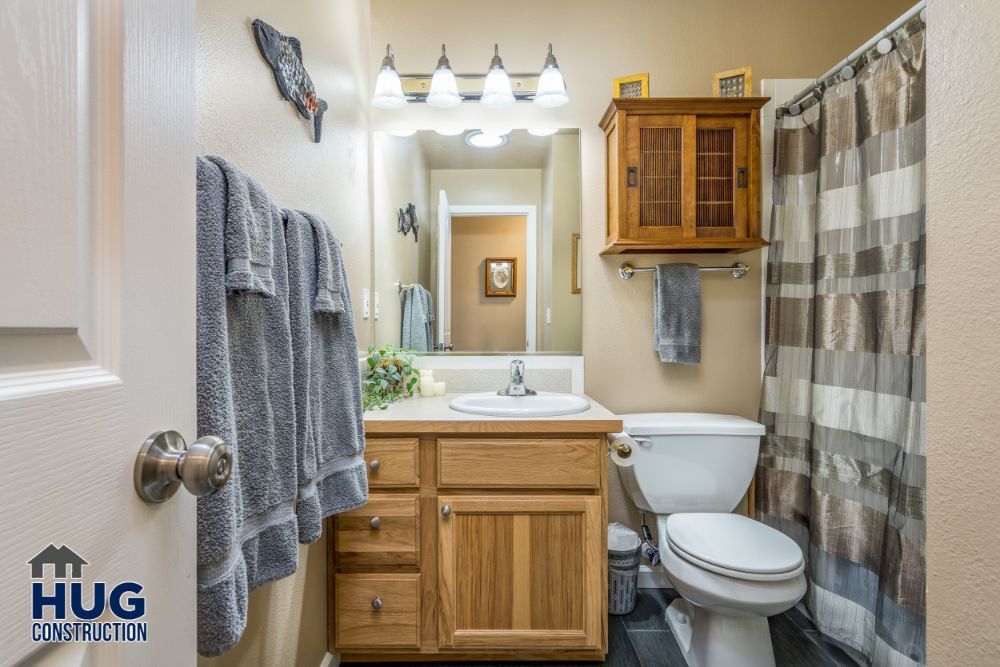 Well-lit bathroom remodel with wooden vanity, wall-mounted fixtures, and striped shower curtain.