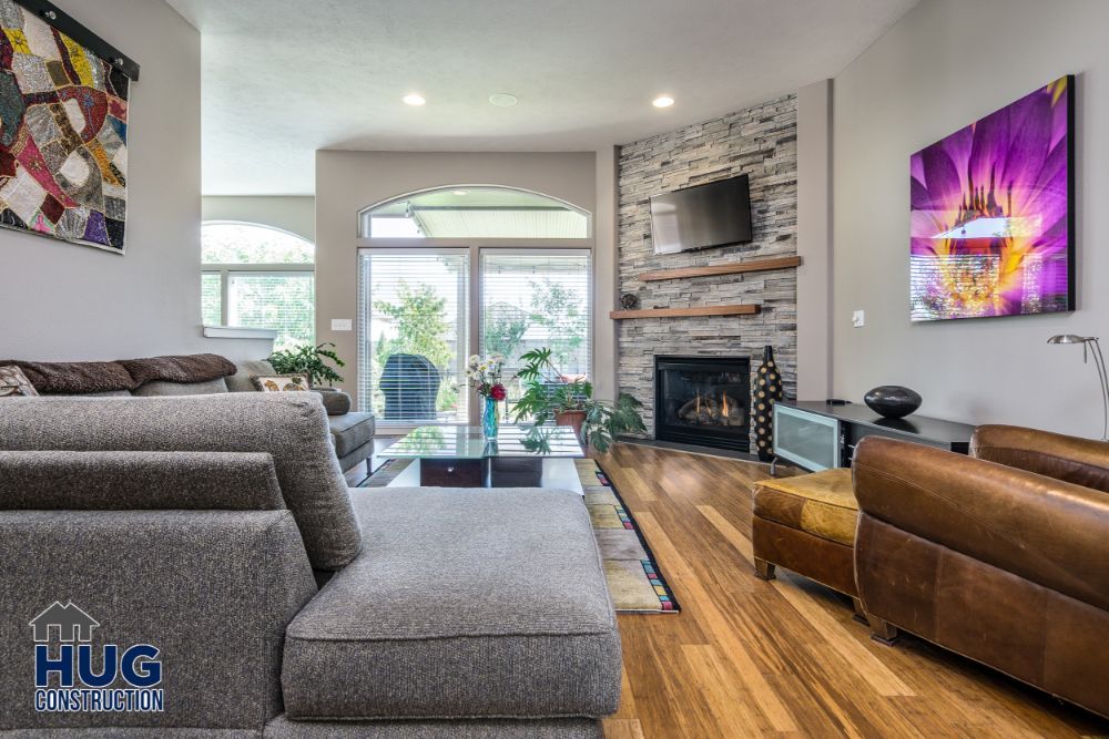 Modern living room featuring remodels and additions like a stone fireplace, large windows, and a mix of contemporary furnishings.