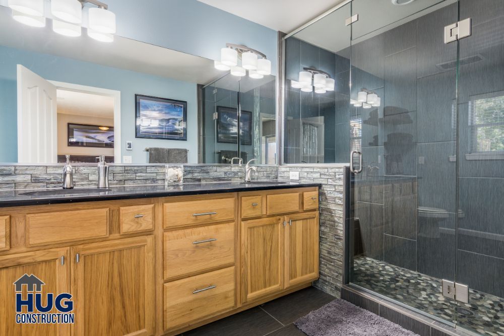 Modern bathroom interior with a glass shower enclosure, wooden vanity unit, dual sinks, and additions.