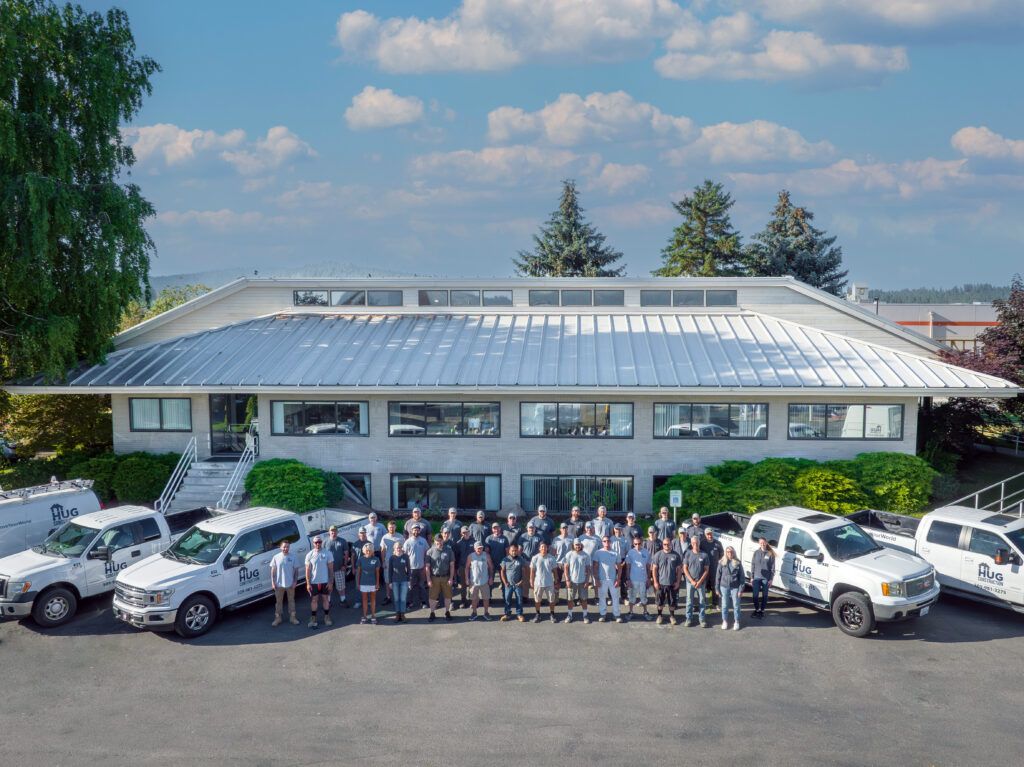 about us hug construction group picture of team in front of the Spokane Valley office with trucks and vans on both sides