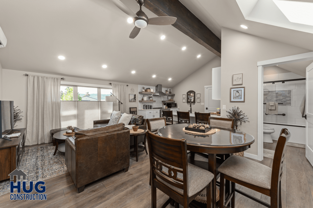 Modern open-plan living and dining area with wooden furniture, vaulted ceiling with exposed beams, and recessed lighting, located at Radio Ln Garage & ADU.