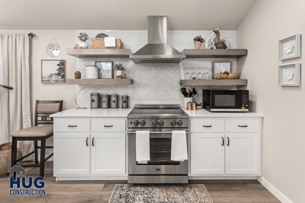 A modern kitchen with white cabinetry, stainless steel appliances, and floating wooden shelves displaying decorative items, highlighted by a stylish radio from Ln Garage & ADU.